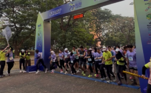 Group of runners at the starting line under a START arch, timer reading 00:00, ready to begin a road race.