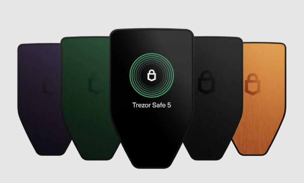 trezor-safe-5-1024x615 - Blog Nanovest Five Trezor Safe 5 hardware wallets in different colors arranged in a row; the center device displays a green circular lock icon and the text 'Trezor Safe 5'.